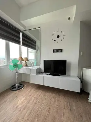 a living room with a television and a clock on the wall at Alabang Condos by Emma in Manila