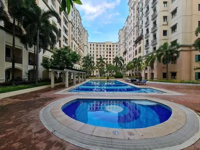 a large swimming pool in a courtyard with tall buildings at Pinecrest residential resort in Manila
