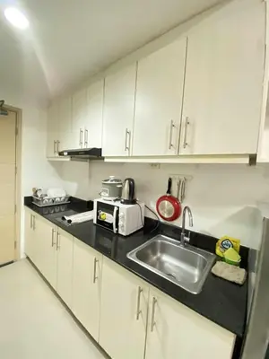 a kitchen with white cabinets and a sink at Ailyn staycation in Manila