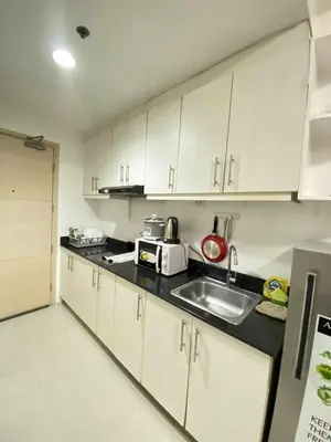 a kitchen with white cabinets and a sink at Ailyn staycation in Manila
