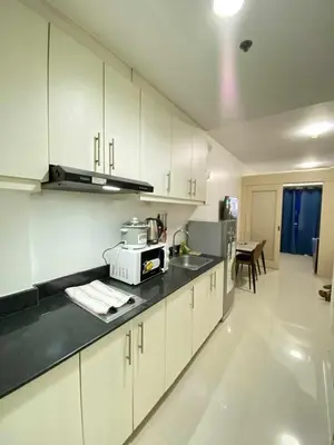 a kitchen with white cabinets and a counter top at Ailyn staycation in Manila