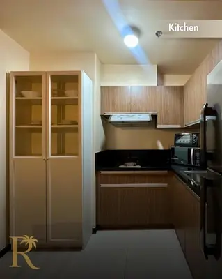 a kitchen with wooden cabinets and a black counter top at Radiance Suite in Manila