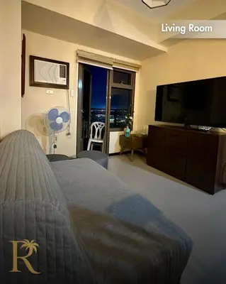 a bedroom with a living room with a bed and a flat screen tv at Radiance Suite in Manila