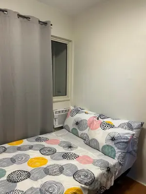 a bedroom with a bed with a comforter and a window at Escapade Home in Manila