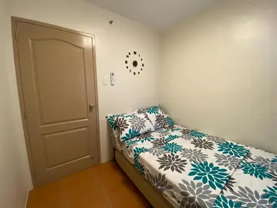 a small bedroom with a bed and a door at Escapade Home in Manila