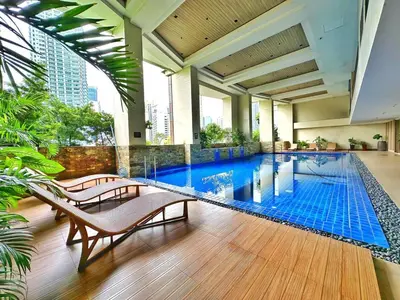 a pool in a building with two chairs and a table at Private Unit at KL Tower Residences near Greenbelt Makati in Manila