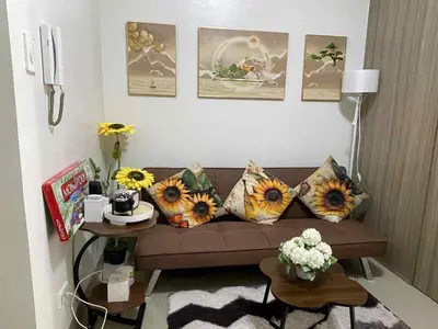 a living room with a couch with sunflower pillows at AJ Staycation Shore 2 in Manila