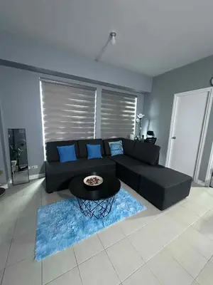 a living room with a black couch and a table at Phebs 2bedroom with pool view in the heart of Makati in Manila