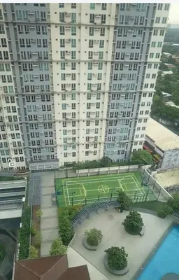 a large building with a tennis court in front of it at Phebs 2bedroom with pool view in the heart of Makati in Manila
