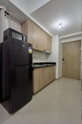 a kitchen with a black refrigerator and wooden cabinets at MOA Shorescape City Life with WiFi in Manila