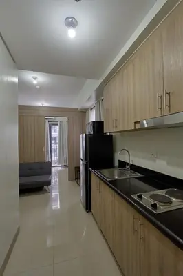 a kitchen with wooden cabinets and a black counter top at MOA Shorescape City Life with WiFi in Manila
