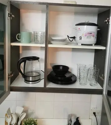 a kitchen cabinet with dishes and appliances in it at Elite Pod Manila in Manila