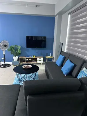 a living room with a black couch and a blue wall at Phebs 2bedroom Posh Condo in the heart of Makati in Manila