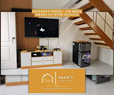 a living room with a tv and a staircase at Arah Cozy House in Dasmariñas