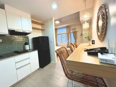 a kitchen with a wooden table and a black refrigerator at Urban Oasis Studio at Central District Makati in Manila