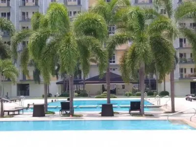 a swimming pool with palm trees in front of a building at Field Residences by Diane in Manila