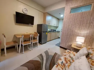 a living room with a couch and a table and a kitchen at Field Residences by Diane in Manila