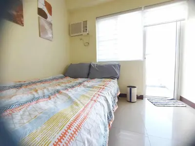 a bedroom with a bed and a large window at Field Residences by Diane in Manila