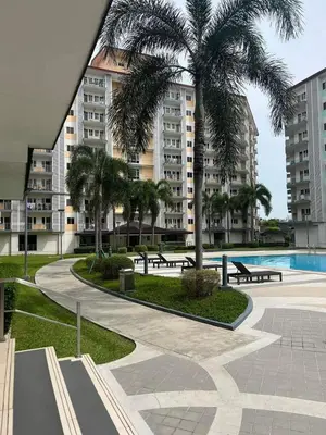 a park with benches and a palm tree and buildings at Field Residences by Diane in Manila