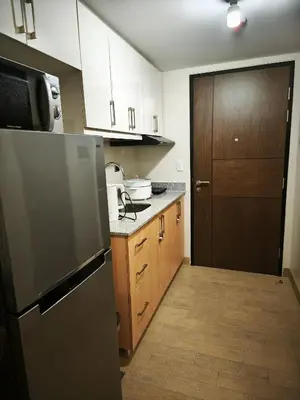 a kitchen with a stainless steel refrigerator and wooden cabinets at Modern Studio Condo in Heart of Quezon City in Manila