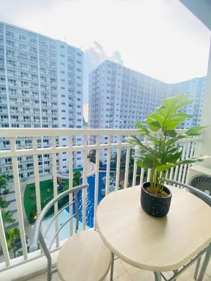 a table with a plant on a balcony with buildings at LiCa Place in Manila