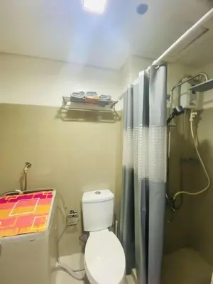 a bathroom with a toilet and a shower with a shower curtain at LiCa Place in Manila
