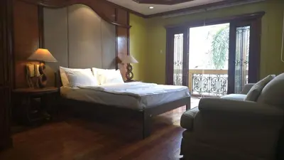 a bedroom with a bed and a window and a couch at Hassan Sisters' EnSuites in Manila