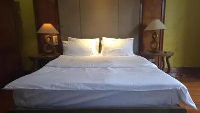 a large bed with white sheets and pillows at Hassan Sisters' EnSuites in Manila