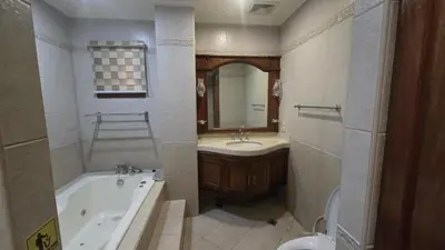 a bathroom with a tub and a sink and a mirror at Hassan Sisters' EnSuites in Manila