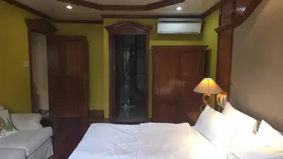 a bedroom with a bed with a lamp and a couch at Hassan Sisters' EnSuites in Manila