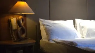 a lamp on a night stand next to a bed at Hassan Sisters' EnSuites in Manila