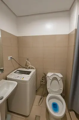 a small bathroom with a toilet and a sink at Cozy 1BR beside MOA with Wifi, Netflix, Pool & Washer in Manila