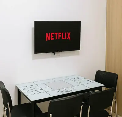 a table with chairs and a television on a wall at Cozy 1BR beside MOA with Wifi, Netflix, Pool & Washer in Manila