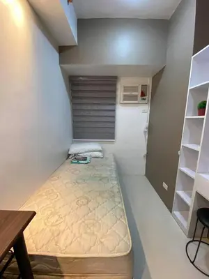 a small room with a bed and a table and shelves at Aral Realty and Property Management in Manila