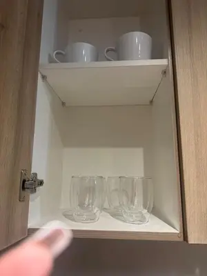 a cabinet with four empty glasses on a shelf at Newly Furnished Staycation near Mall of Asia in Manila