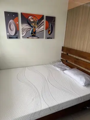 a white bed in a room with paintings on the wall at Newly Furnished Staycation near Mall of Asia in Manila