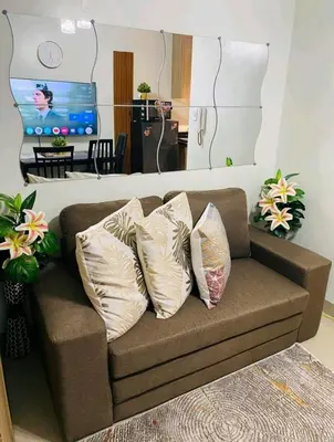a couch with three pillows on it in a living room at Newly Furnished Staycation near Mall of Asia in Manila