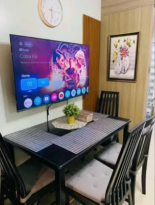 a dining room table with a computer monitor on a wall at Newly Furnished Staycation near Mall of Asia in Manila