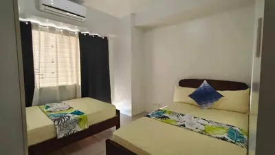 a small bedroom with two beds and a window at 1148a 3br 1-king size 1queen size 2 double size 2-single size 1-extra matress Moa view in Manila