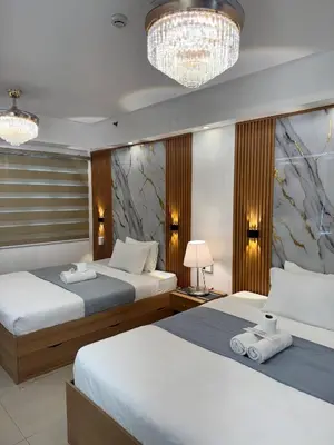 a hotel room with two beds and a chandelier at Relax in Pasay Citys Best Kept Secret - Spacious Condo with Garden View in Manila