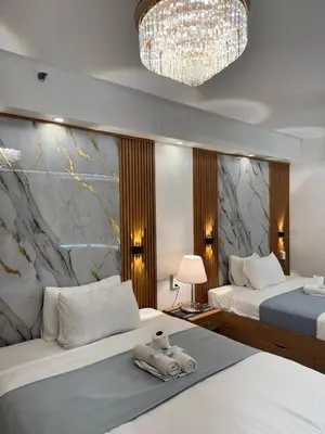 a hotel room with two beds and a chandelier at Relax in Pasay Citys Best Kept Secret - Spacious Condo with Garden View in Manila