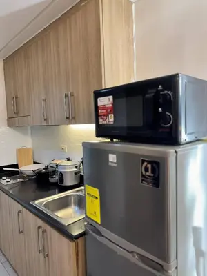 a kitchen with a microwave on top of a refrigerator at Relax in Pasay Citys Best Kept Secret - Spacious Condo with Garden View in Manila