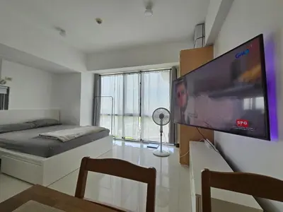 a living room with a large flat screen tv on a wall at Cozy Corner Studio in McKinley Walk to Venice Mall in Manila