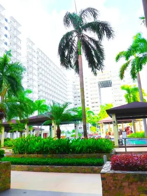 a palm tree in front of a large building at Shell Residences MOA 2 beds by Dad's in Manila