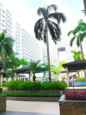 a palm tree in front of a large building at Shell Residences MOA 2 beds by Dad's in Manila