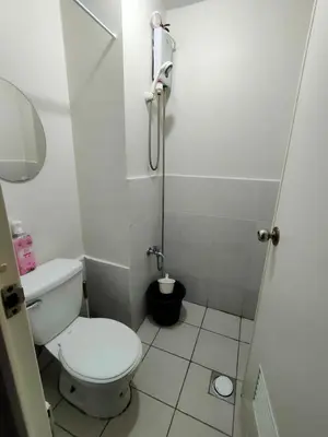 a small bathroom with a toilet and a shower at Trisha's Condotel Urban Deca Tower Edsa in Manila