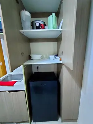 a small refrigerator in a kitchen with shelves at Trisha's Condotel Urban Deca Tower Edsa in Manila