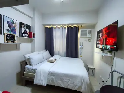 a bedroom with a white bed and a window at Trisha's Condotel Urban Deca Tower Edsa in Manila