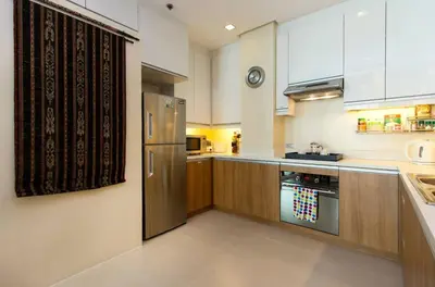 a kitchen with a stainless steel refrigerator and wooden cabinets at Elegant 2BR Apartment in Upscale Fort BGC Fast Wifi in Manila