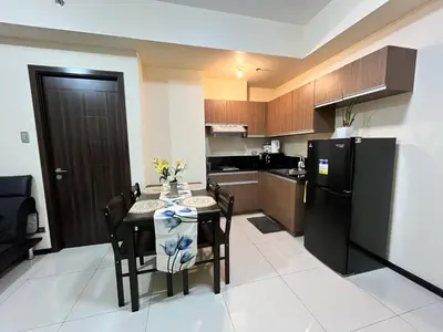 a kitchen with a table and a black refrigerator at Bayfront Staycation at The Radiance Manila Pet-Friendly, Free Pool & Gym near Airport, MOA, Star City, Manila World Trade Center & Manila Bay in Manila